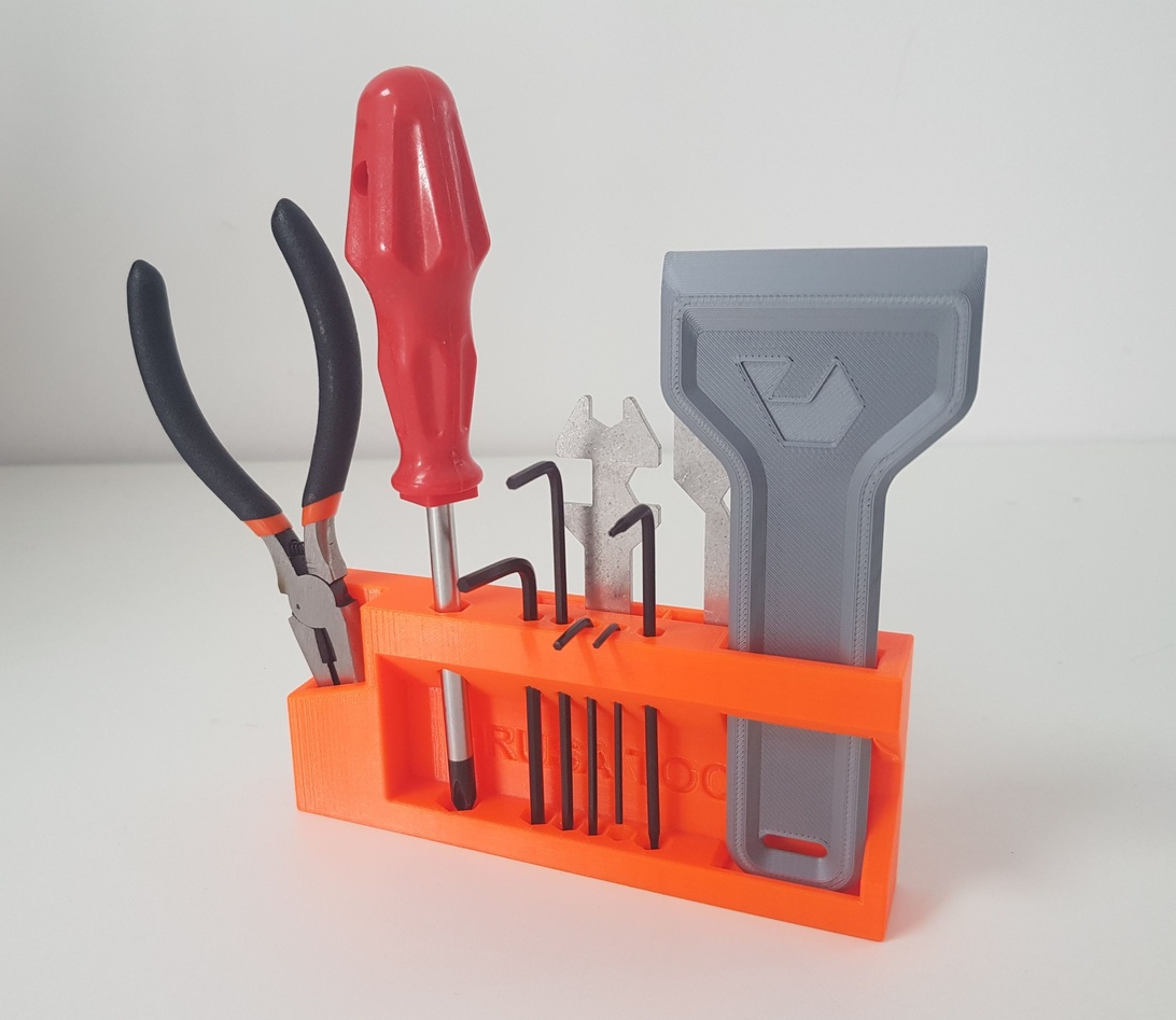 En ljusorange 3D-printad verktygshållare med diverse småverktyg.